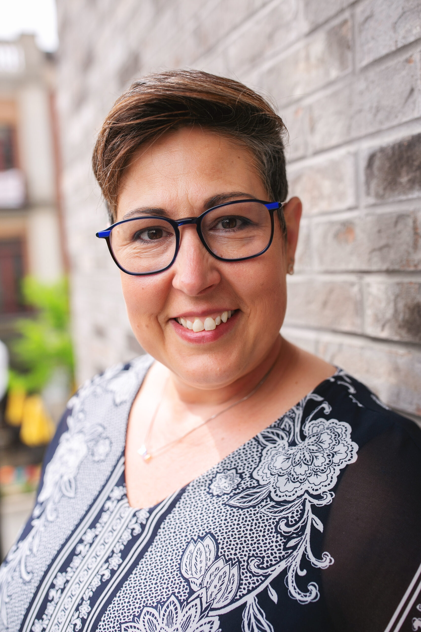 Eve Keller with glasses and smiling, shoulder up picture, blue, flowery shirt.